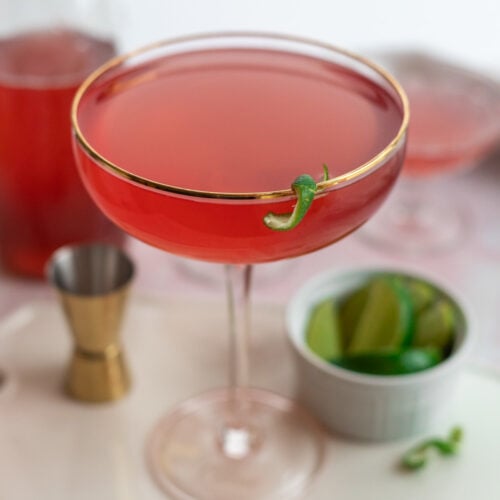 A Cosmopolitan in a martini glass garnished with lime zest