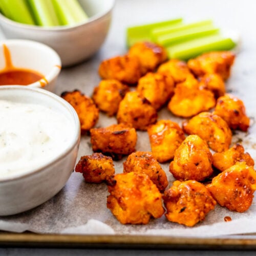 Mouthwatering Cauliflower Poppers covered in sauce with celery and ranch sauce