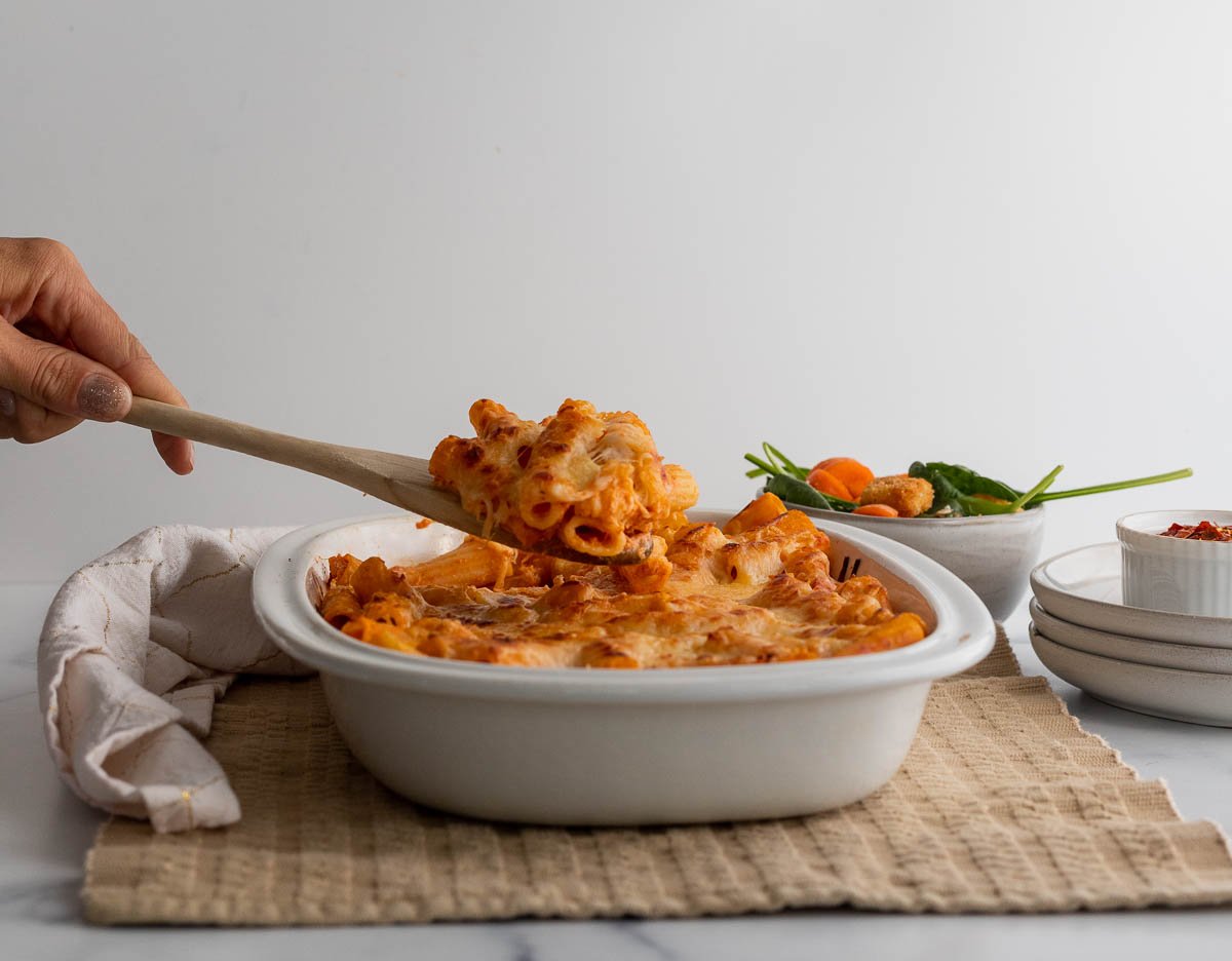 Serving a chunk of baked ziti from a casserole dish