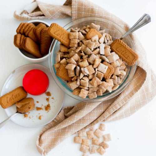 Biscoff Cookie Butter Chex Mix placed in a large mixing bowl with extra cookies and cookie butter.
