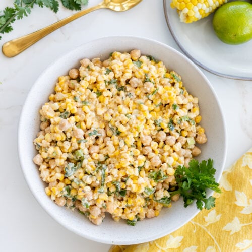A large bowl of chickpea salad with a serving spoon and cilantro.